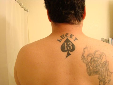 1989 Ford Bronco - Tattoos of a spade with 'Lucky 13' and a jester adorn a man's back.