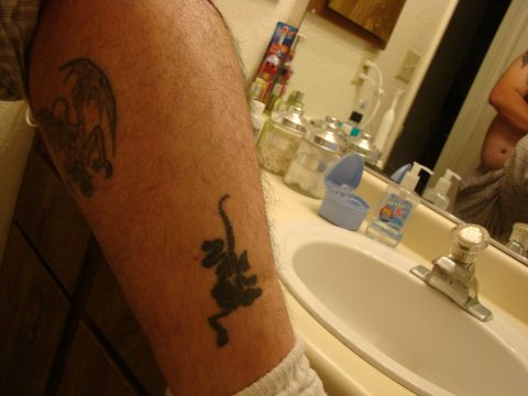 1989 Ford Bronco - Leg tattoos include a dragon and a dinosaur, with a bathroom sink visible in the reflection.