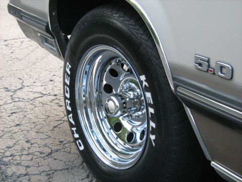 1988 Mercury Grand Marquis - Close-up of a chrome wheel and tire with white lettering, alongside a '5.0' badge on the vehicle's side.