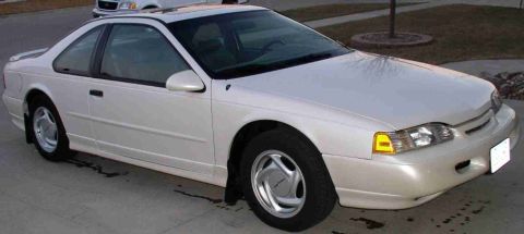 1994 Ford Thunderbird - White 1994 Ford Thunderbird coupe parked on a driveway, showing its front 3/4 view.