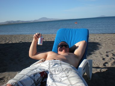 1993 Ford Bronco - A man enjoys a sunny day at the beach, holding a beverage while relaxing in a chair.