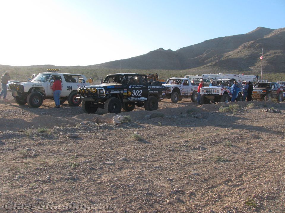 Off-road race trucks staged in desert with white 301 and black 302