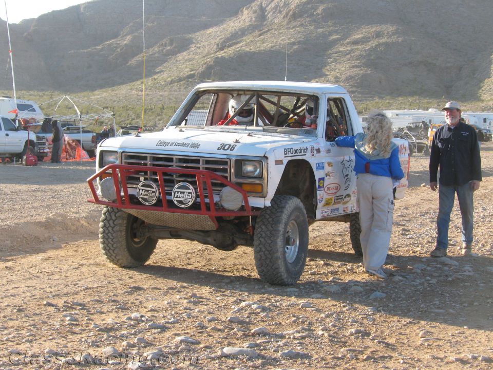 White number 306 Ford race truck with two people standing beside it