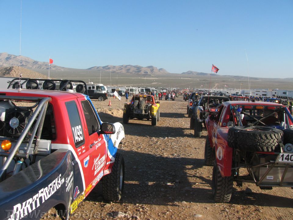 Dense rows of off-road race trucks and buggies staged in desert