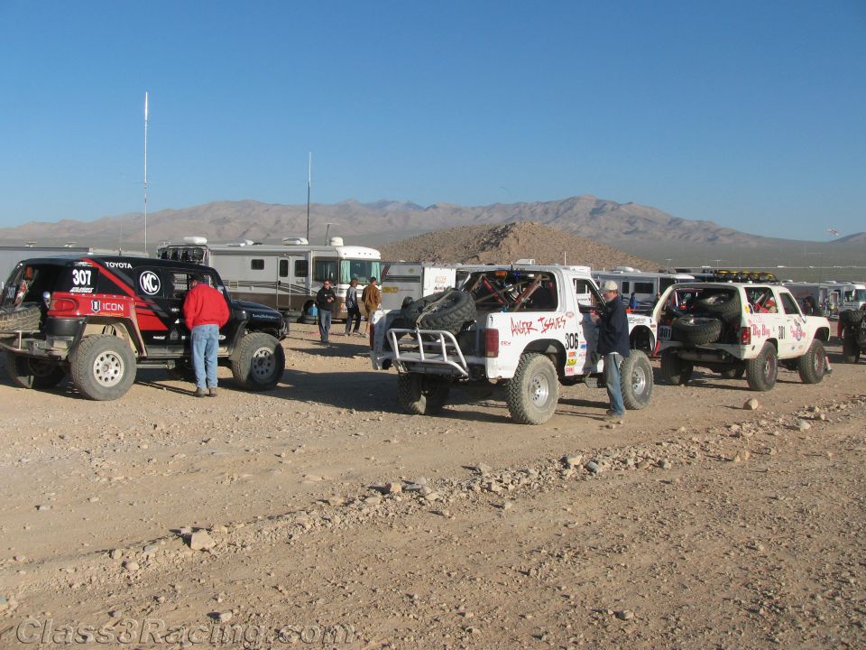 Off-road race trucks staged near RVs and trailers in open desert