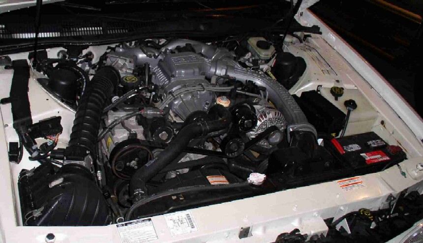 Supercharged V6 engine bay in a white car seen from the passenger side