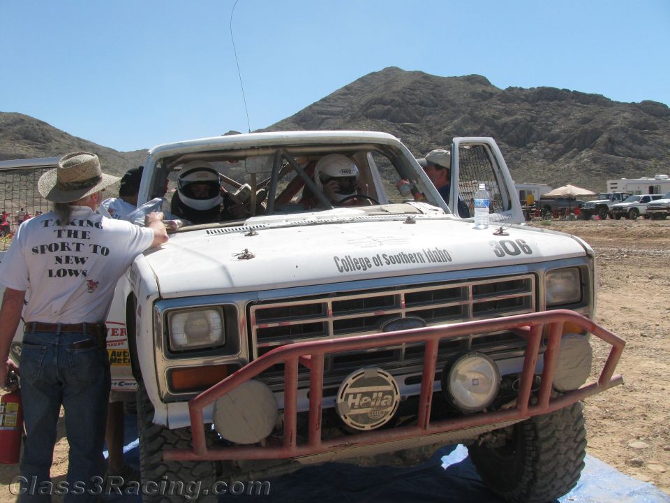 White Ford race truck 306 with crew, man in T-shirt reading Taking the Sport to New Lows
