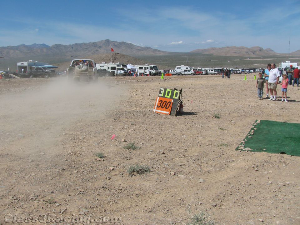 Desert race course with 300 marker board, dust trail and spectators