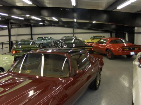1979 Chevrolet Camaro - A collection of vintage automobiles are stored indoors, with a prominent red Camaro visible in the background.