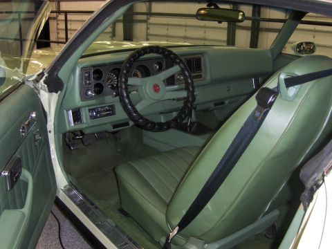 1979 Chevrolet Camaro - The interior of a car shows a green dashboard, steering wheel, and seats, with a visible radio and gauges.