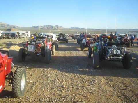 1990 Ford Bronco - Numerous tube-frame off-road buggies, including numbers 1304 and 1305, are staged closely together on gravel in a desert valley.
