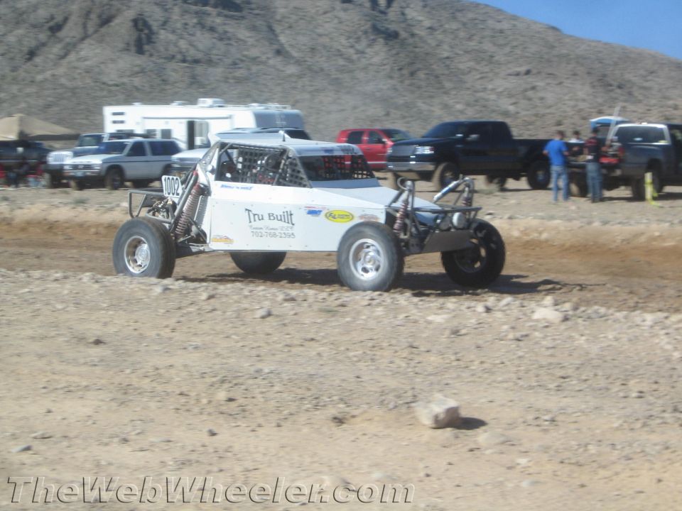 White tube-frame off-road buggy marked Tru Built racing on a dirt track