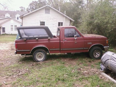 1987 Ford F-150 - Side view of a red 1987 Ford F-150 pickup truck with a black camper shell.