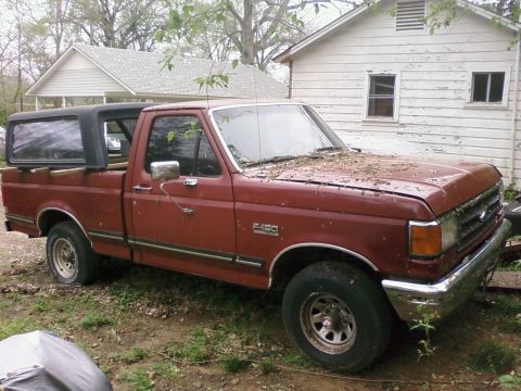 1987 Ford F-150 - This 1987 Ford F-150 pickup truck is parked in a yard with a camper shell on the bed.