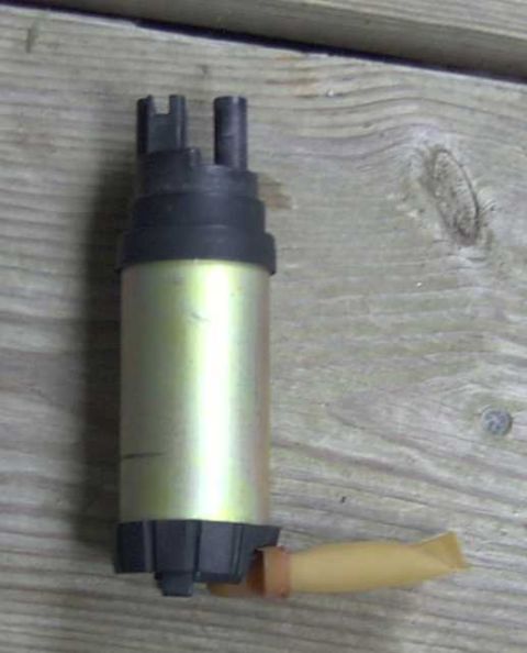 1997 Ford Taurus - A fuel pump with a yellow filter and black connectors is shown against a wooden background.