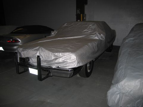 1991 Ford LTD Crown Victoria - A car covered with a silver tarp is parked indoors, with other vehicles also covered.