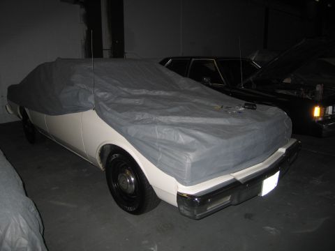 1991 Ford LTD Crown Victoria - Two cars are parked indoors, one is covered by a tarp.