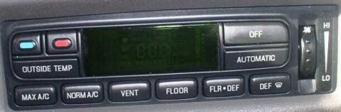 1999 Ford Crown Victoria - Close-up of a car's interior climate control system, showing various function buttons and a temperature dial.
