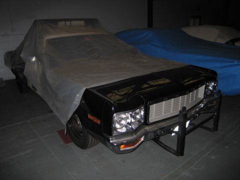 1991 Ford LTD Crown Victoria - A black car, partially covered, sits in a garage with another vehicle covered in blue.