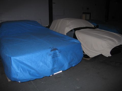 1991 Ford LTD Crown Victoria - Multiple vehicles are covered in tarps inside a garage or storage unit.