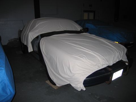 1991 Ford LTD Crown Victoria - Two vehicles are parked indoors and covered with protective car covers.
