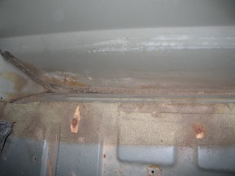 1991 Ford LTD Crown Victoria - Rust and corrosion are visible on the metal floor of a vehicle's interior.