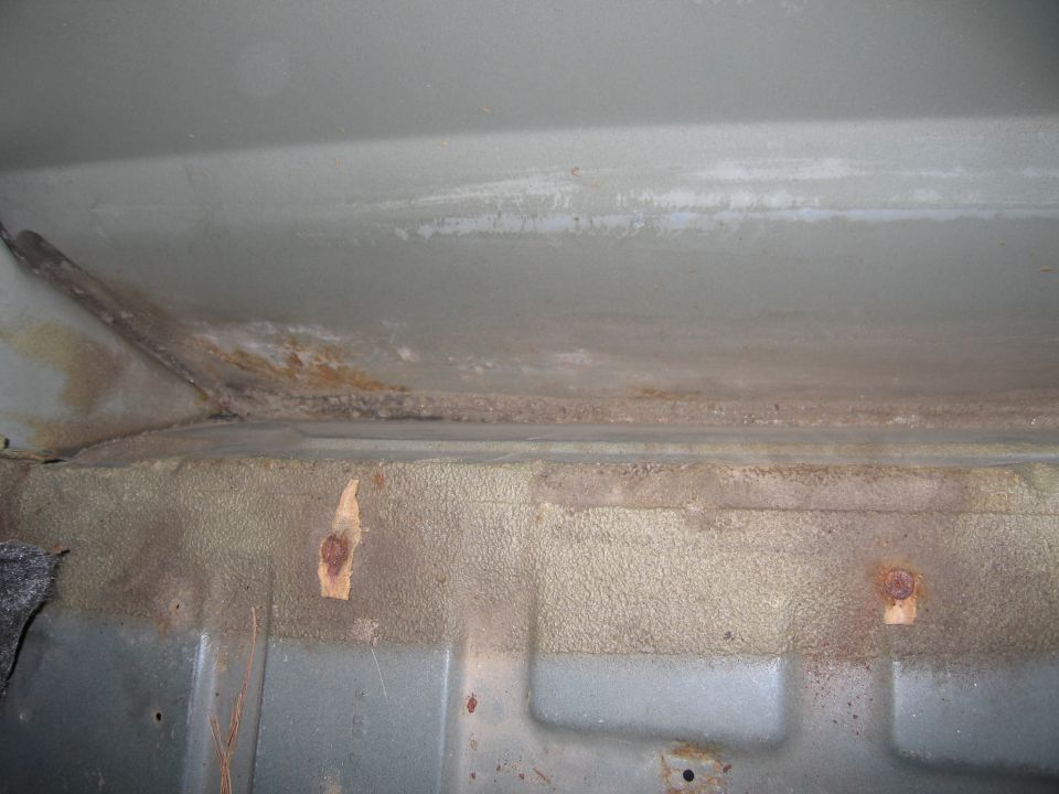 Vehicle interior floor showing rust and corrosion on metal surfaces