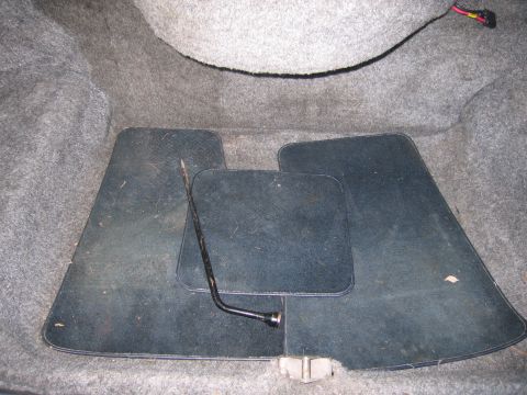 1991 Ford LTD Crown Victoria - The trunk interior shows dark floor mats and a jack tool, with gray carpeting lining the space.