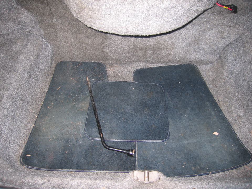 Trunk interior with dark floor mats and a jack tool
