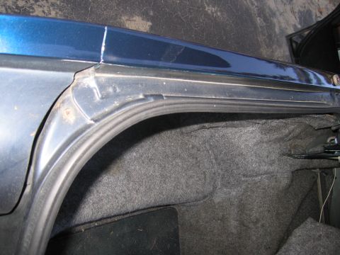 1991 Ford LTD Crown Victoria - The interior of a car's trunk shows gray carpeting and the edge of the blue body panel.