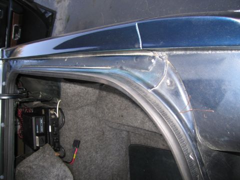 1991 Ford LTD Crown Victoria - A CB radio is mounted inside the trunk area of a dark blue vehicle, with visible wiring and carpeting.