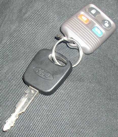 1999 Ford Crown Victoria - A Ford key with a remote fob attached rests on a dark, textured surface.