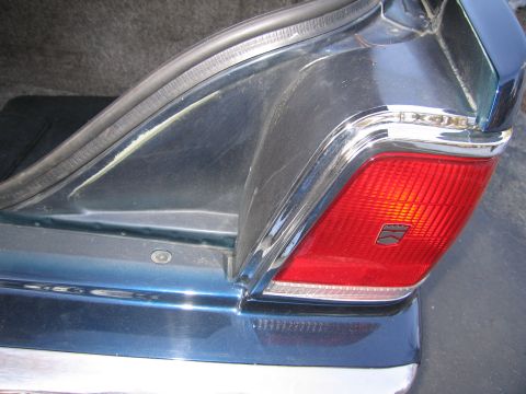 1991 Ford LTD Crown Victoria - Close-up view of the rear quarter panel and taillight assembly on a dark blue vehicle.