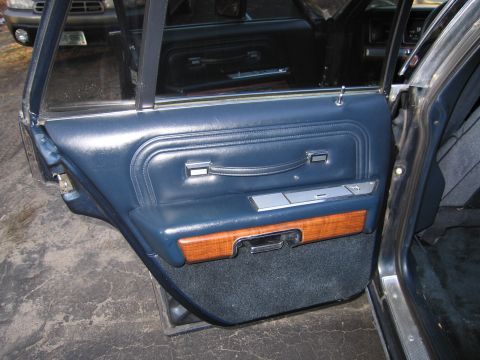 1991 Ford LTD Crown Victoria - Close-up of the interior door panel, showing blue upholstery and wood grain trim.