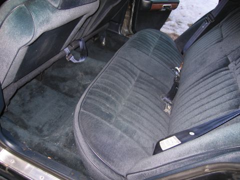 1991 Ford LTD Crown Victoria - The interior of a car shows dark blue velour rear seats and carpeting, with seatbelts fastened.