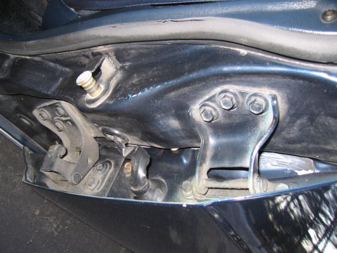 1991 Ford LTD Crown Victoria - Detail of a car's door hinge mechanism, showing metal brackets and fasteners.