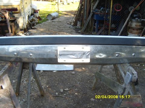 1989 Ford Bronco - A chrome rear bumper is shown mounted on sawhorses, with a license plate frame visible.
