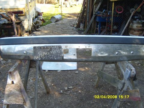 1989 Ford Bronco - A chrome bumper with a handwritten sign attached, reading 'THIS IS FOR WALTERIS P.B.C.', is displayed on sawhorses.