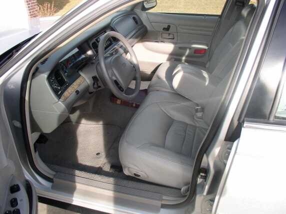 Gray leather interior of a 1998 Ford Crown Victoria, showing the front seats, dashboard, and steering wheel from the passenger side