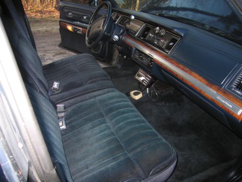 1991 Ford LTD Crown Victoria - The interior of a Ford Crown Victoria features plush velour seats and wood-grain trim on the dashboard.