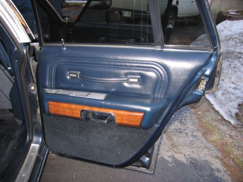 1991 Ford LTD Crown Victoria - The interior door panel of a vehicle, blue vinyl and wood accents, with the door ajar.