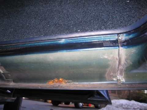 1991 Ford LTD Crown Victoria - Rust and damage are visible on the lower part of a green car door sill.