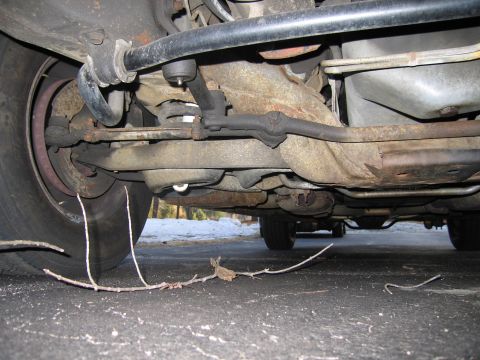 1991 Ford LTD Crown Victoria - Close-up of the front suspension and steering linkage on the underside of a vehicle.