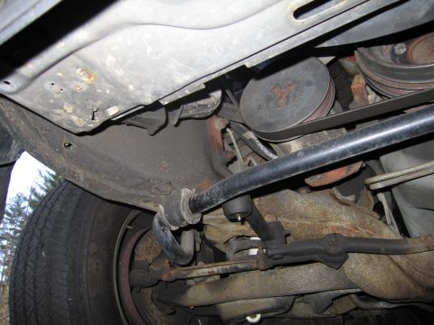 1991 Ford LTD Crown Victoria - Close-up of the vehicle's undercarriage, showing the sway bar and engine pulleys.