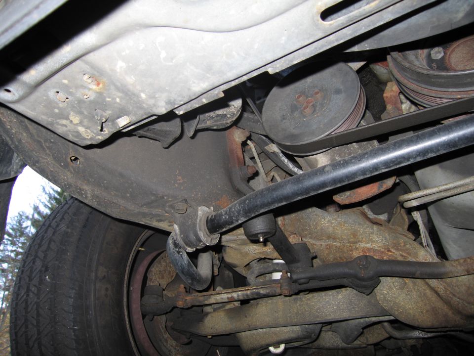 Underside view of a car's suspension and engine belt system