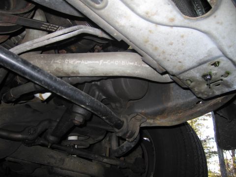 1991 Ford LTD Crown Victoria - Undercarriage view of a vehicle, focusing on suspension parts and a metal pipe with embossed text.