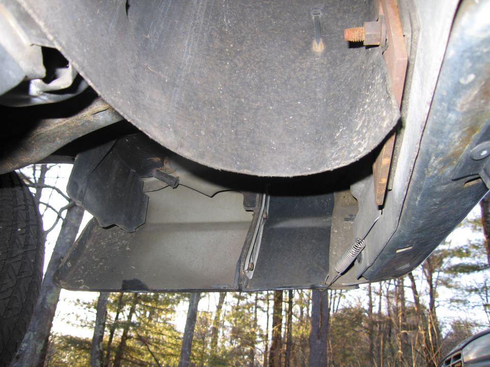 Underside view of a vehicle's front bumper and fender liner with visible bolts and springs