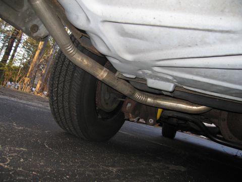 1991 Ford LTD Crown Victoria - A low-angle view of the undercarriage of a vehicle, revealing the exhaust system and a rear tire.
