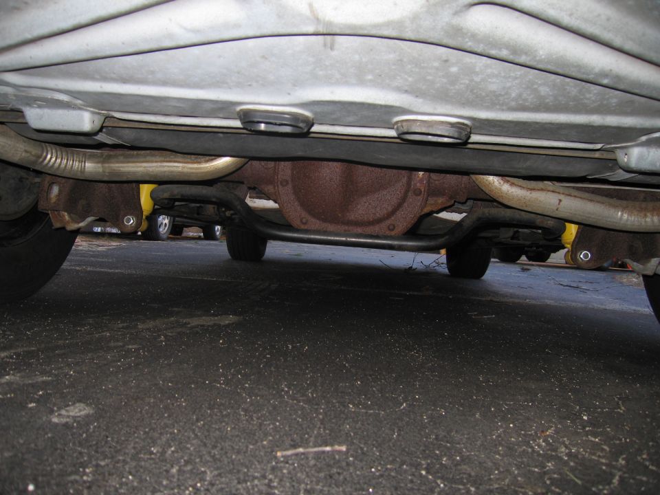 Underside view of a car showing the rear differential, exhaust pipes, and suspension components