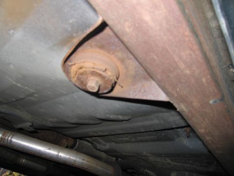 1991 Ford LTD Crown Victoria - Close-up view of the undercarriage, showing an exhaust pipe and a rusted suspension part.
